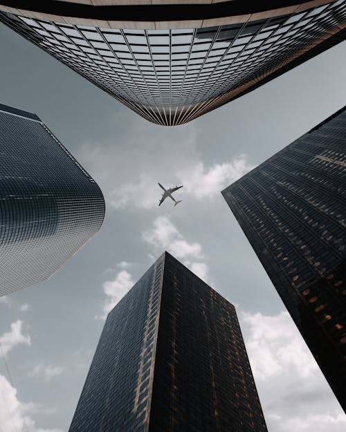 Airplane Flying Over City Buildings in Low Angle Photography