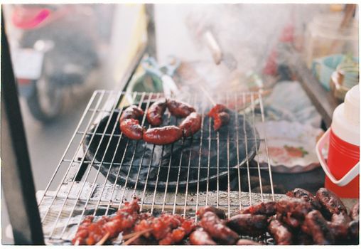 Tasty sausages grilling on a smoky BBQ. Perfect outdoor cooking scene.