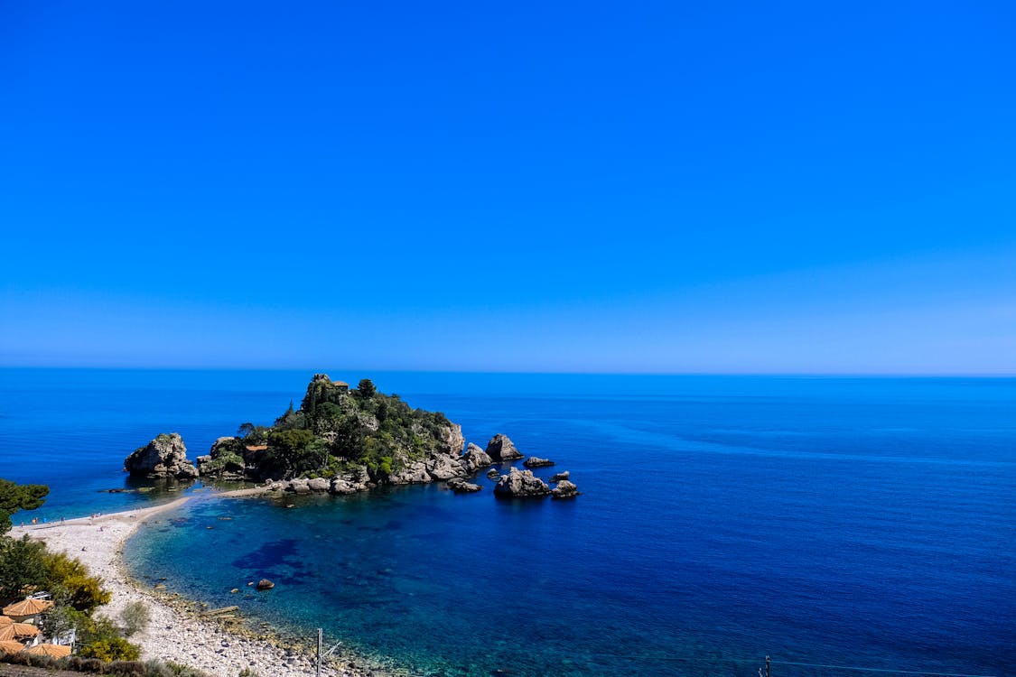 免費 白天在藍天下的灰色岩石附近的白色沙灘海岸線 圖庫相片