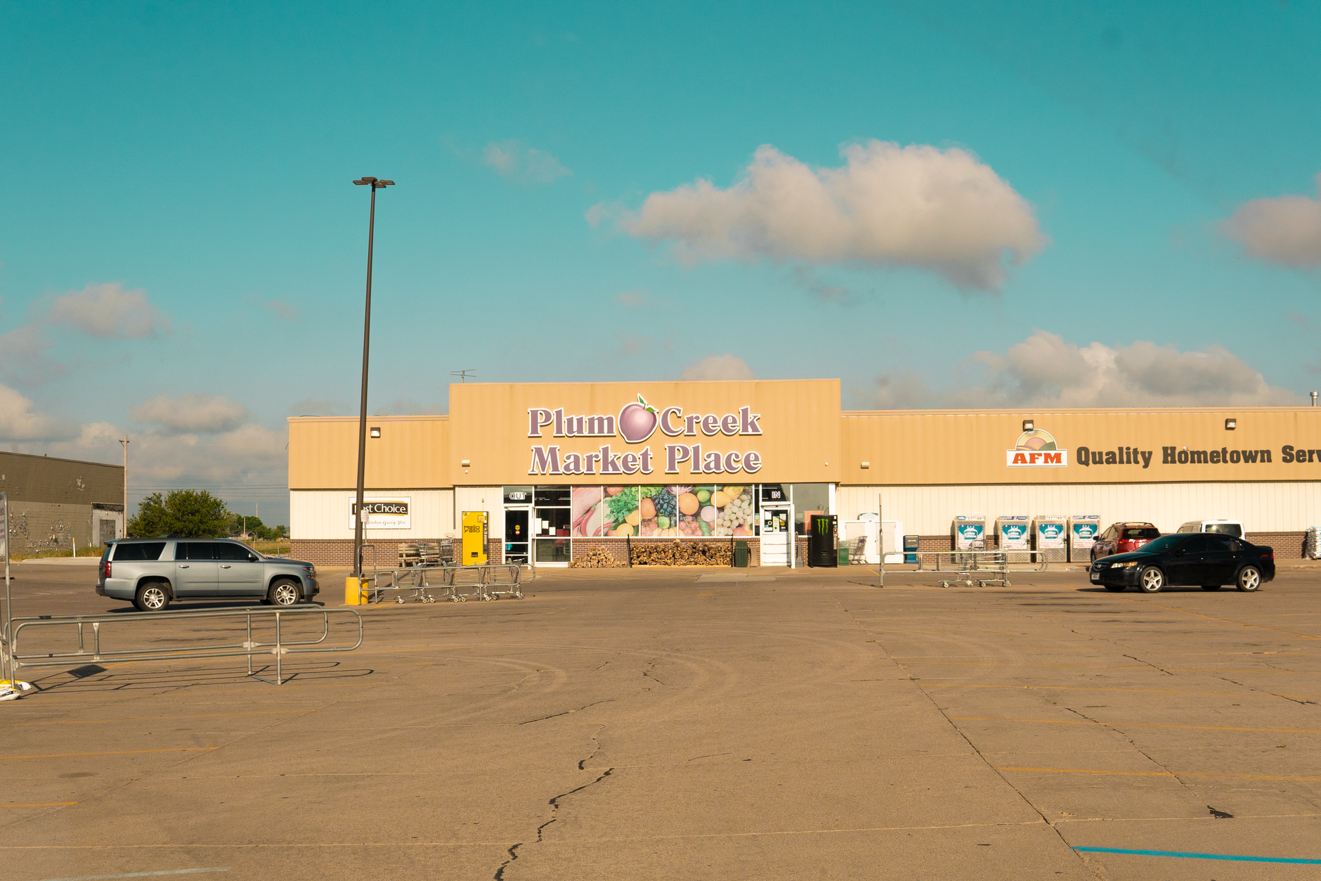Front view of Plum Creek Market Place with empty parking lot under a clear sky.