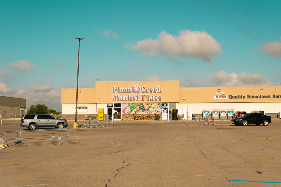 Front view of Plum Creek Market Place with empty parking lot under a clear sky.