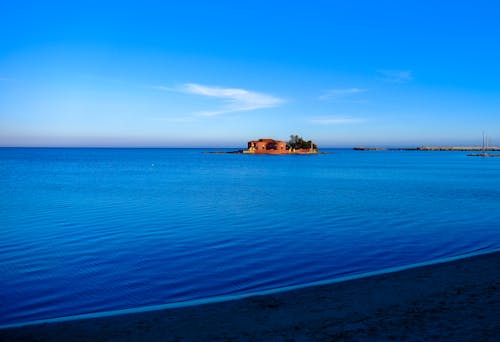 Brown Coated House on Blue Body of Water Under Clear Skies during Daytime