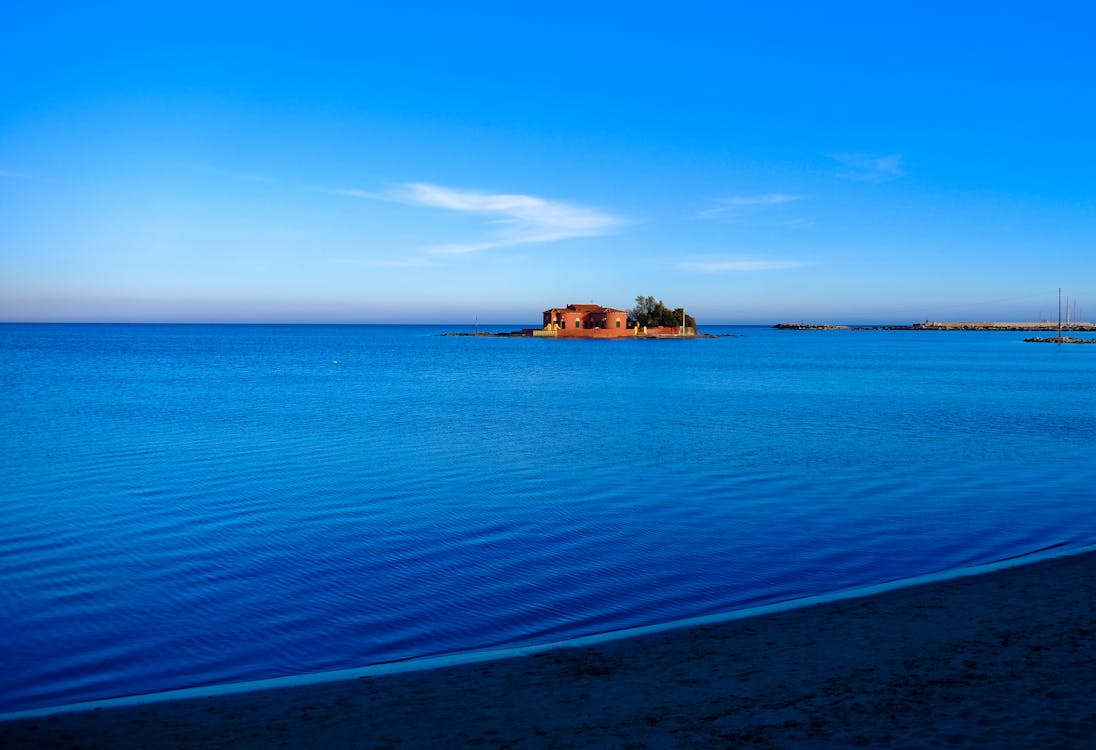 бесплатная Коричневый дом на синем водоеме под ясным небом в дневное время Стоковое фото