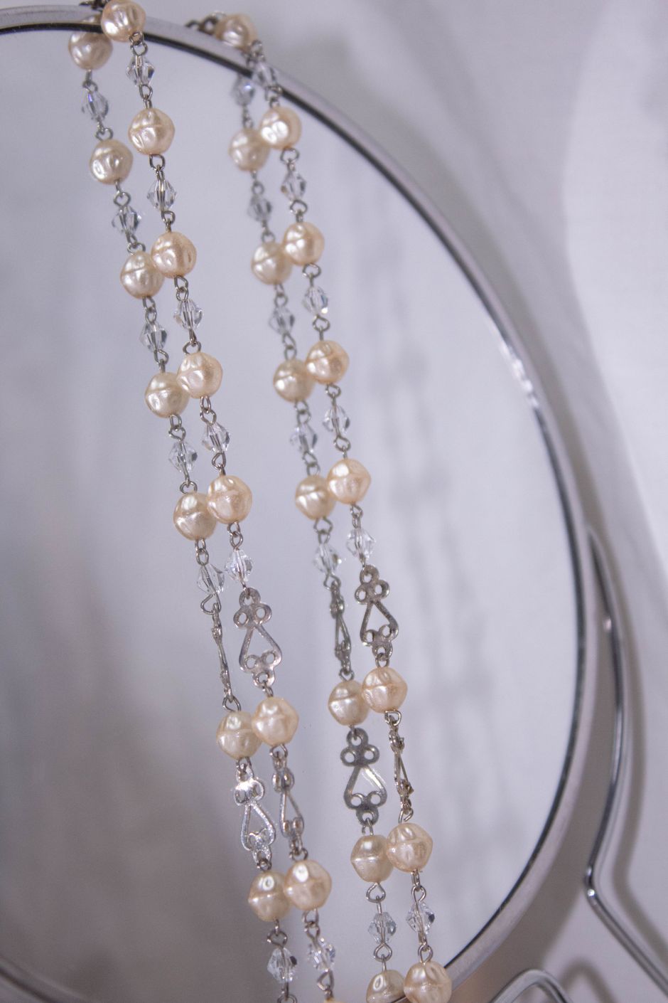 Pearl necklaces and delicate chains reflected on a mirror