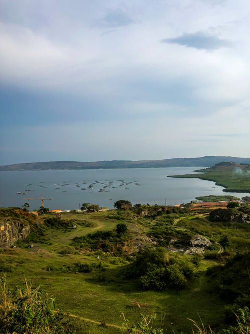 Free A picturesque aerial view of a serene lake surrounded by lush countryside under a cloudy sky. Stock Photo