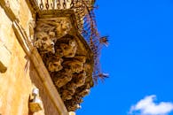 阳台上矗立着历史悠久的巴洛克石像鬼雕塑，错综复杂的造型映衬着清澈的蓝天