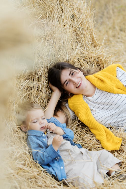 Woman in Yellow Sweater Lying on Brown Grass Field with Her Son