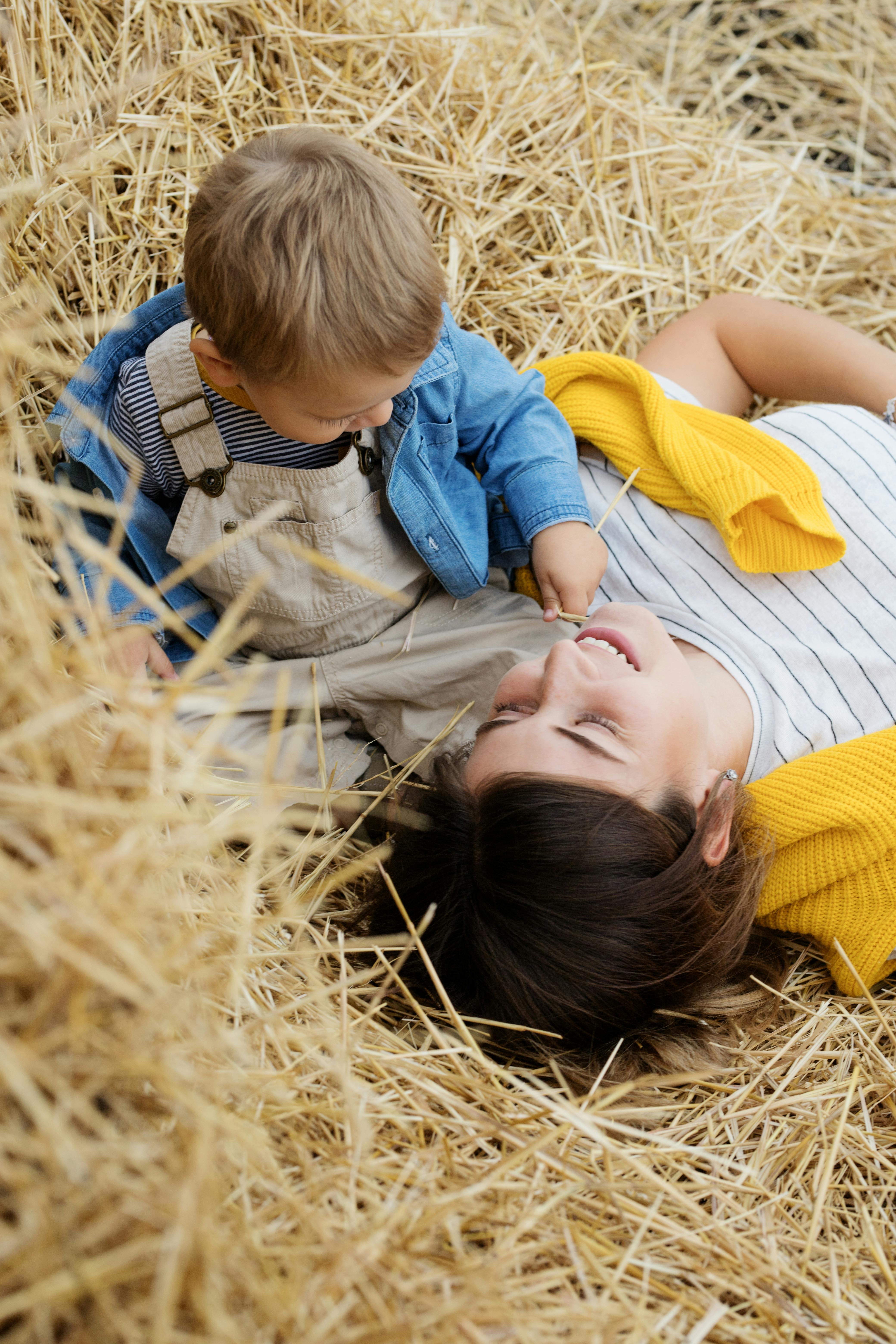 a boy sitting beside a woman lying on a hay stack
