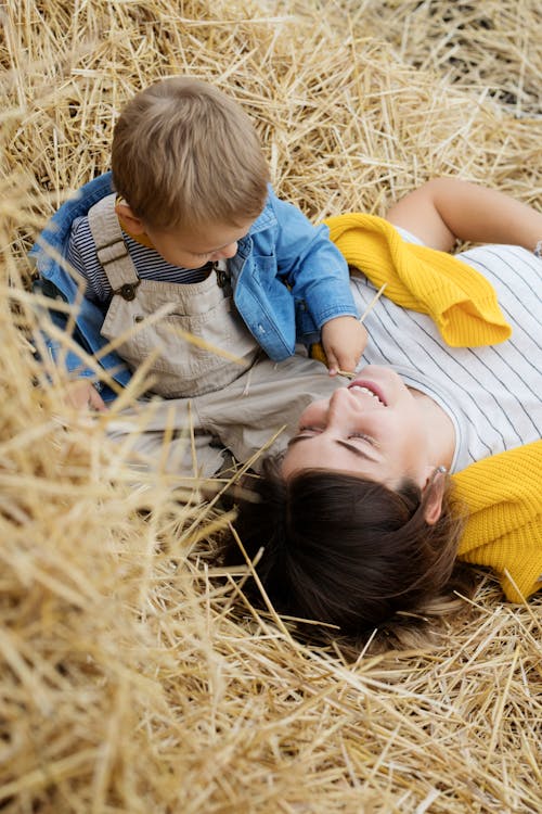 A Boy Sitting Beside a Woman Lying on a Hay Stack 