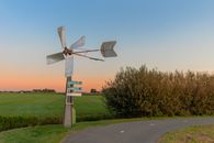 A Metal Wind Vane on Green Grass Near a Walkway
