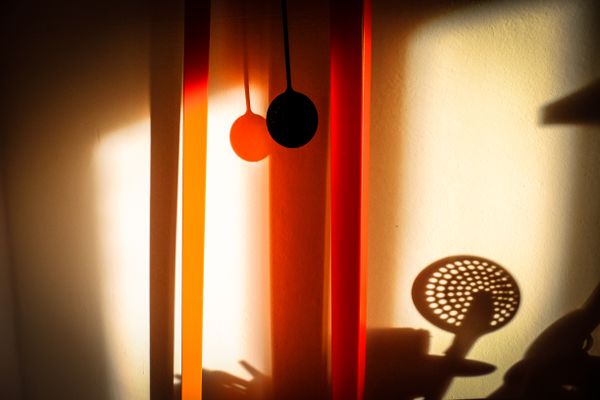 Orange light and object silhouettes on a wall, photo by Francesco Ungaro on Pexels