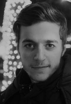 Captivating black and white portrait showcasing a young man's face with decorative bokeh lights in the background.