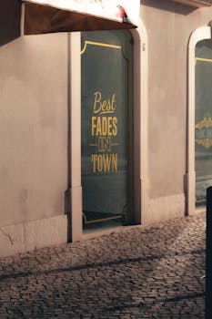 Rustic cobblestone street with a shopfront displaying 'Best Fades in Town' text.