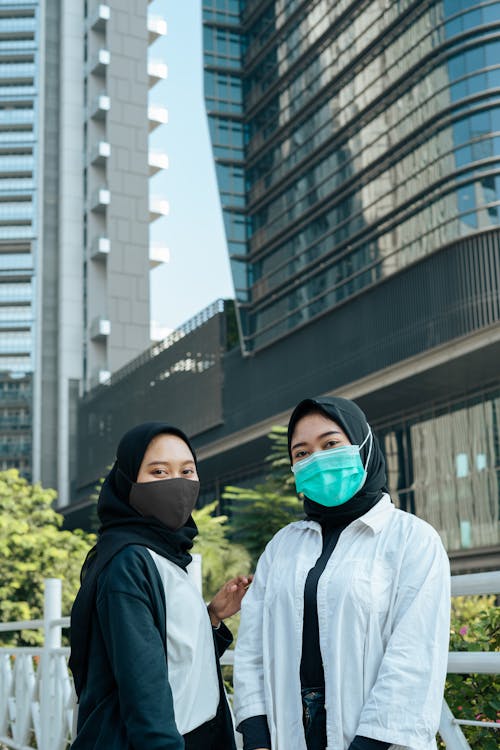 Woman in Blue Jacket Beside Woman in White Long Sleeves Shirt Wearing Facemask