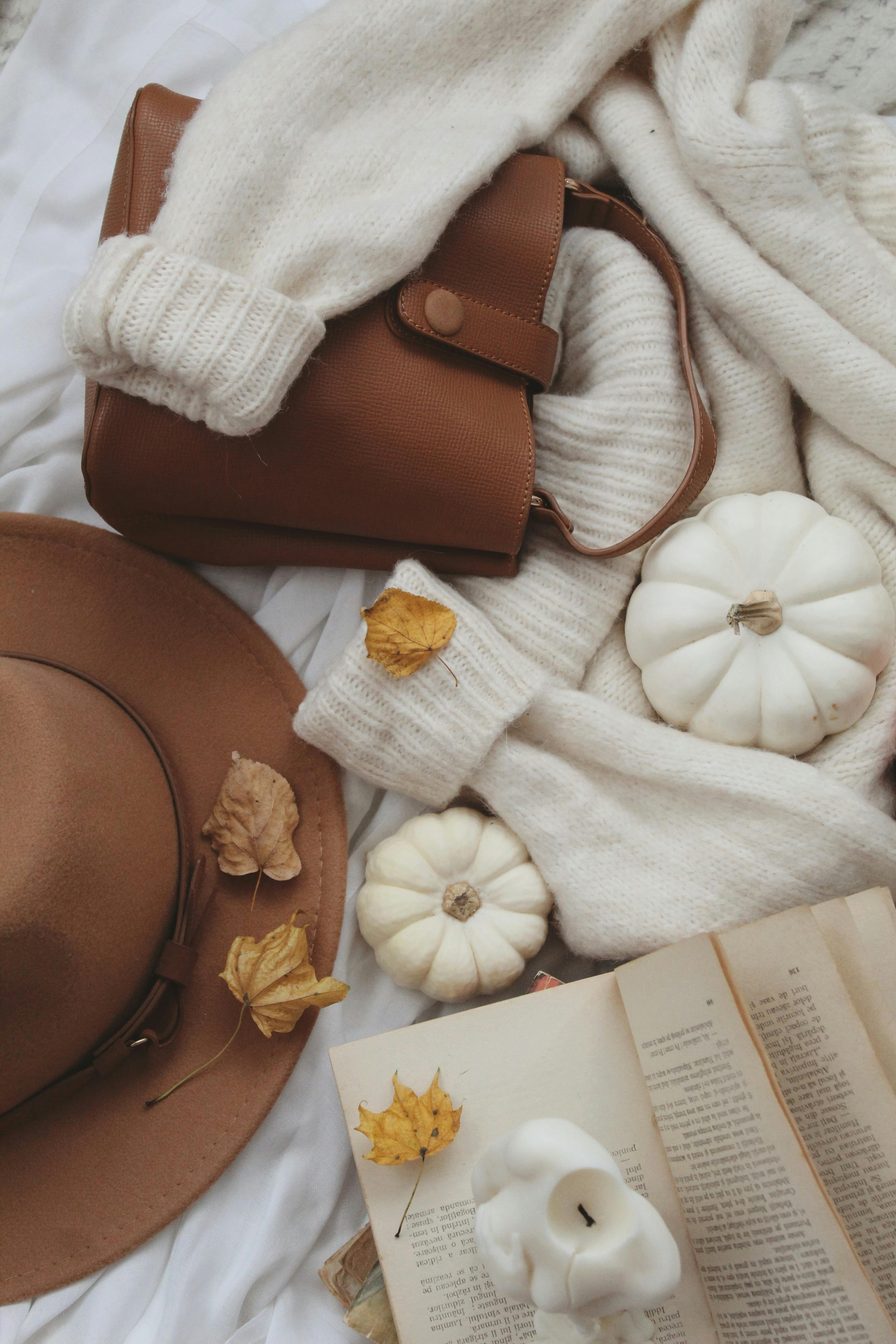 Warm autumn scene with sweater, pumpkins, and accessories, evoking cozy lifestyle vibes.