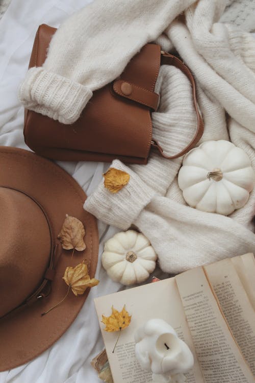 Candles, autumn leaves and bronze bag on sweater