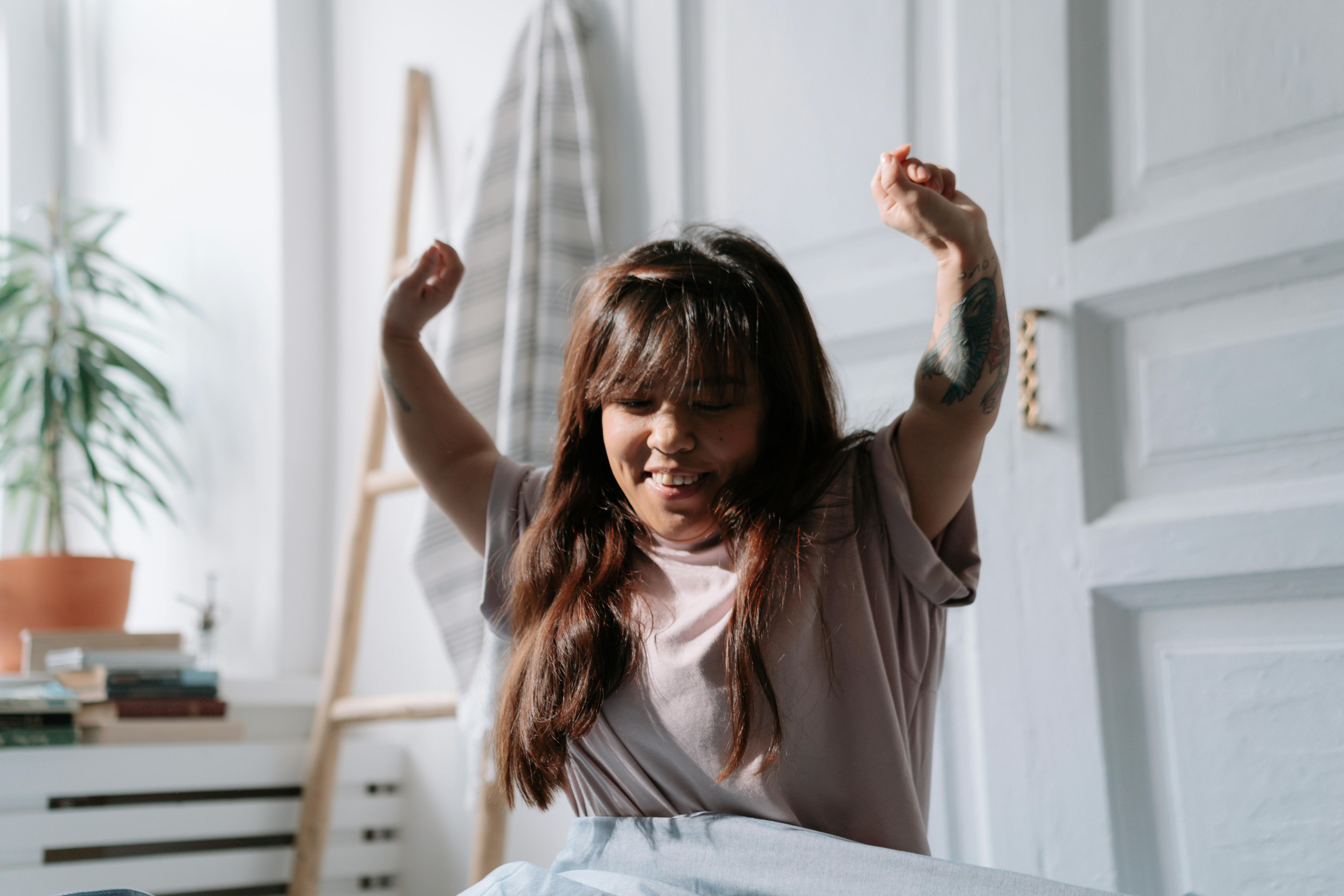 woman waking up refreshed in the morning with natural light coming through window and a peaceful expression
