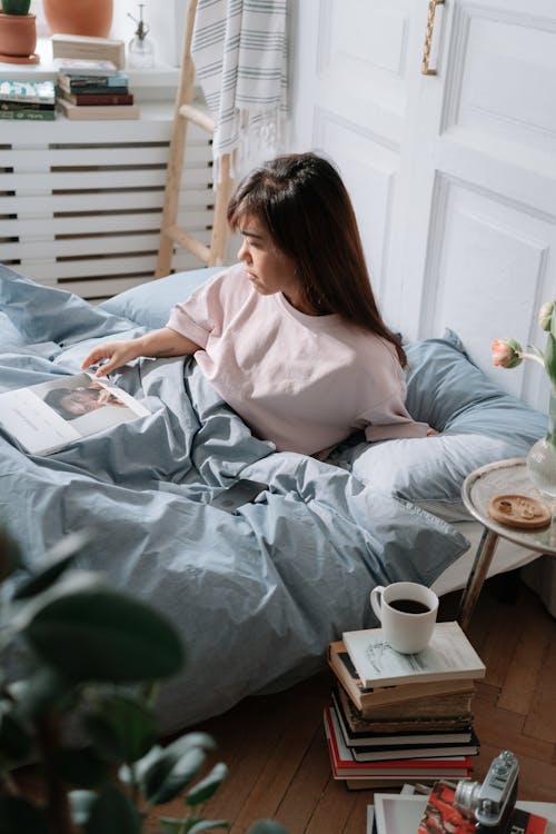 Free Woman with dwarfism reading book in bed Stock Photo