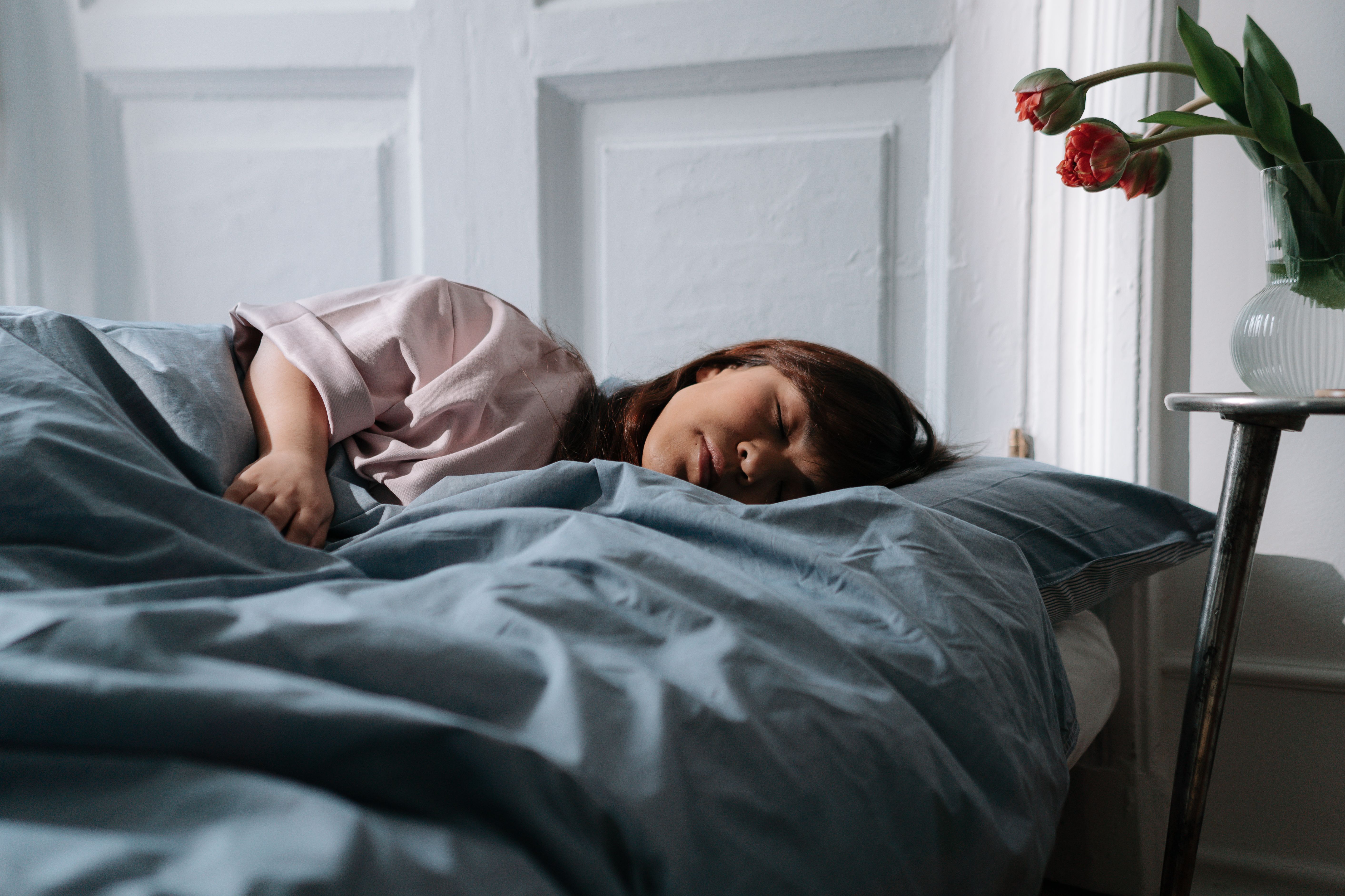 Asian woman peacefully sleeping in a cozy bedroom, showcasing morning tranquility and relaxation.