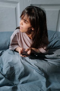 Asian woman with disability relaxing in bed holding a smartphone during a bright morning.