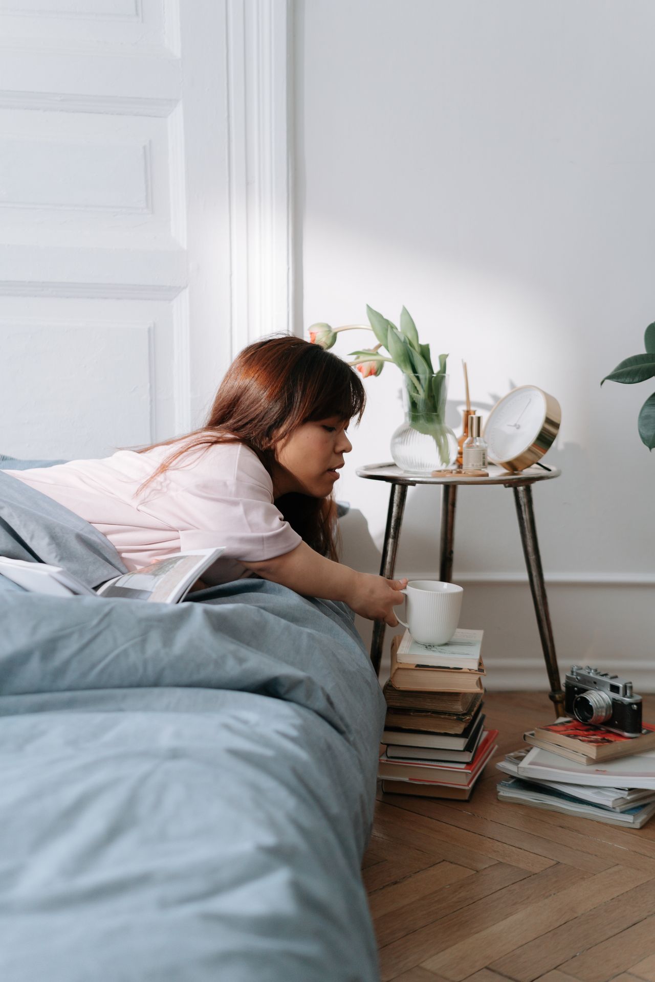 Woman in a pink jersey pajama top stretching in bed