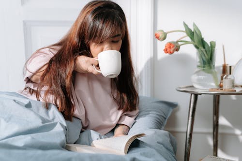 Free Woman with dwarfism drinking coffee in bed Stock Photo