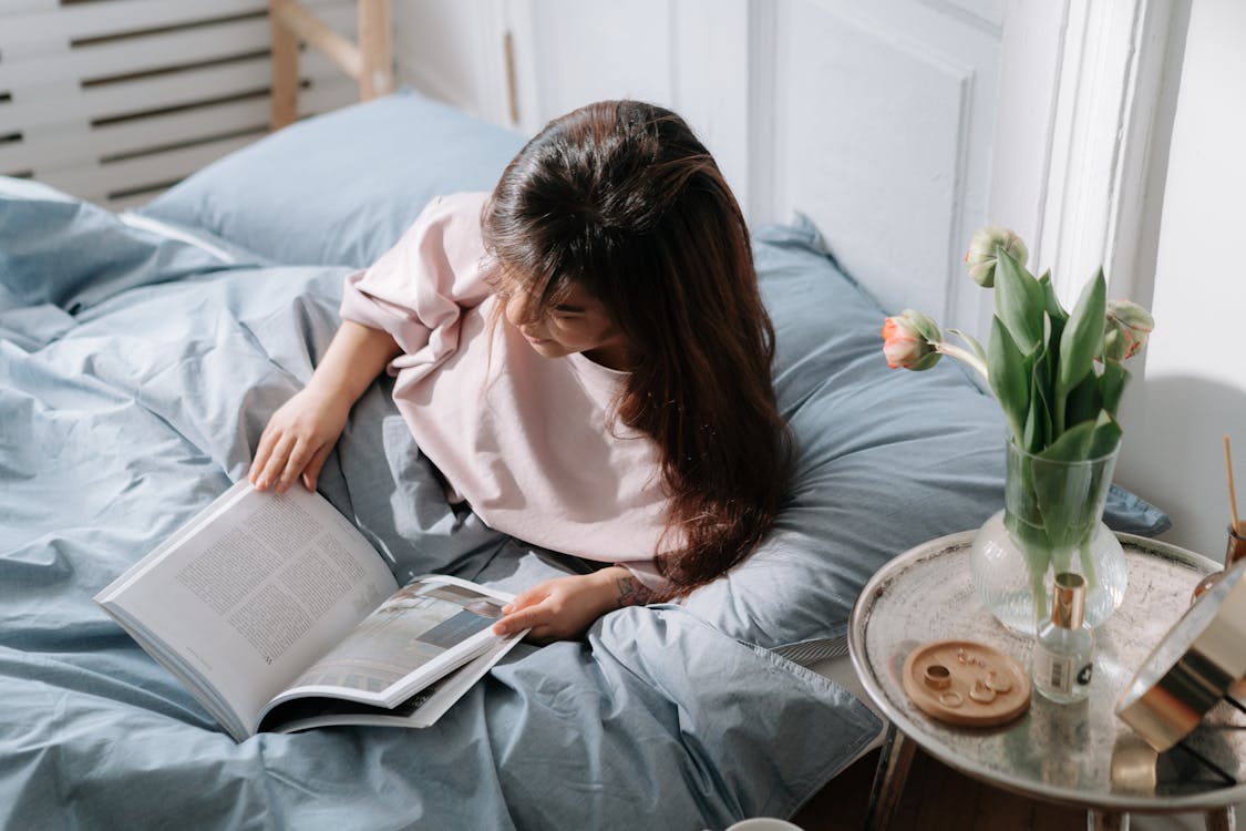 Free Woman with dwarfism reading book in bed Stock Photo