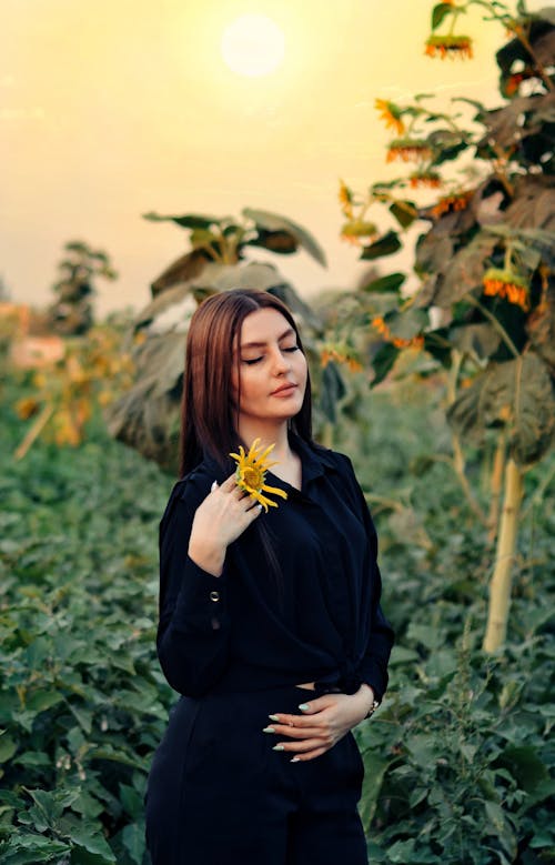 Woman in Black Long Sleeve Holding Yellow Flower