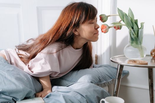 Young dwarf woman smelling flowers in vase on table