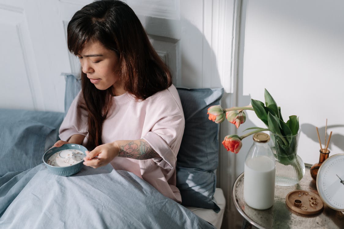 Free Woman eating cereal with milk sitting in a bed Stock Photo