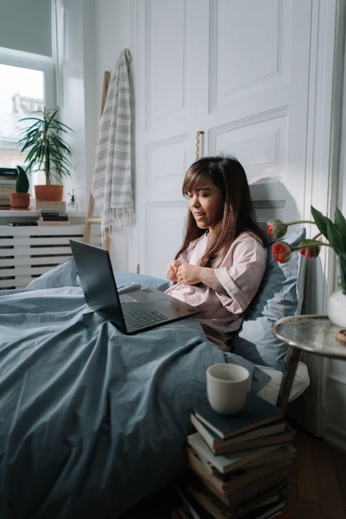 Free Woman with a laptop sitting in bed Stock Photo