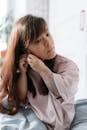 Girl with dwarfism sitting in bed and touching her right ear with hands