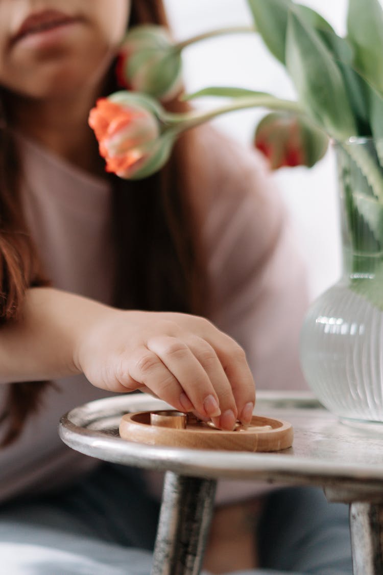 Female Hand Picking Up Jewellery From Wooden Plate 