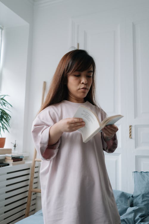 Free Woman reading a book in a bedroom Stock Photo