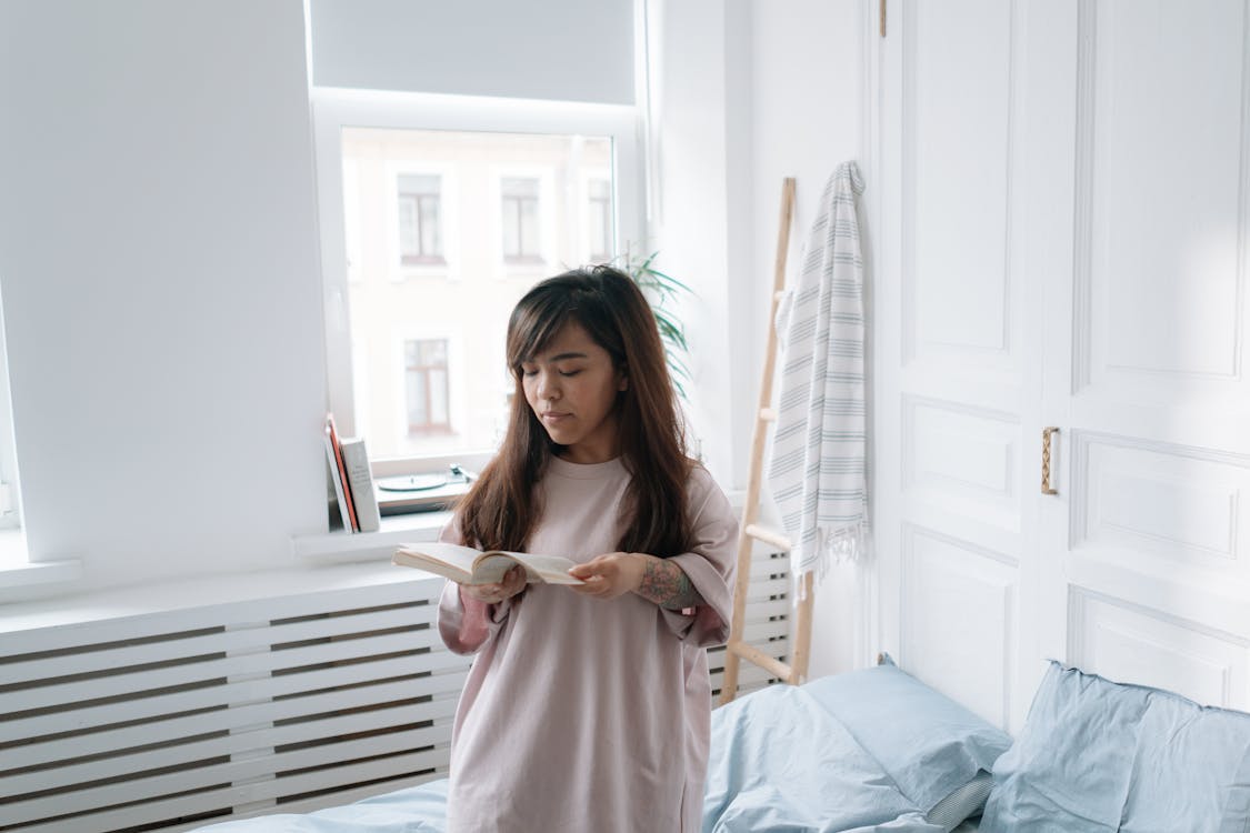 Free Woman reading a book in a bedroom Stock Photo