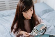 Young dwarf woman doing her makeup before mirror