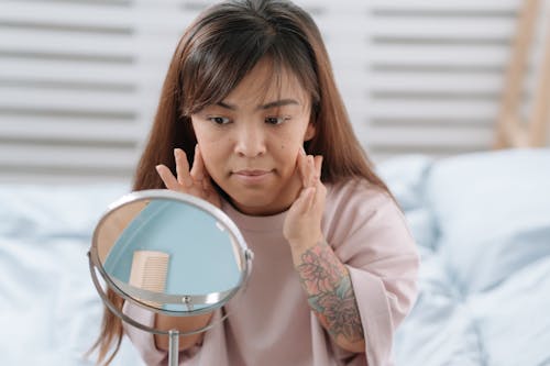 Free Woman Touching Cheeks Looking in the Mirror Stock Photo