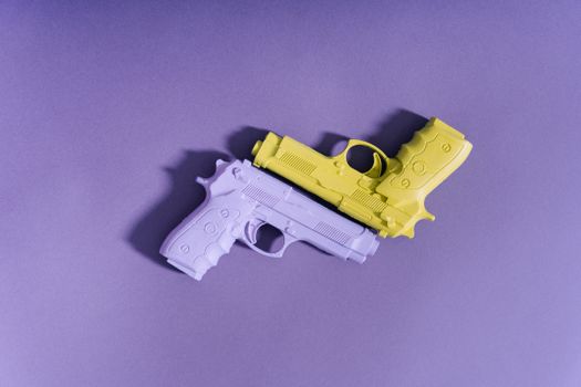 Purple and yellow toy guns arranged on a purple surface, forming a playful flat lay.