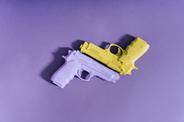 Flatlay Photo Of Yellow And Purple Toy Guns