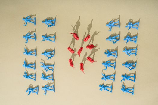 Blue and red toy soldiers arranged on a yellow background with artistic shadows.