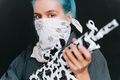 Photograph of a Woman with Blue Hair Holding a Black and White Rifle