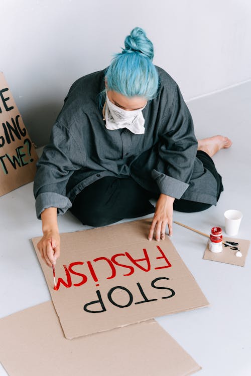 Photo of a Woman with Blue Hair Painting on a Cardboard
