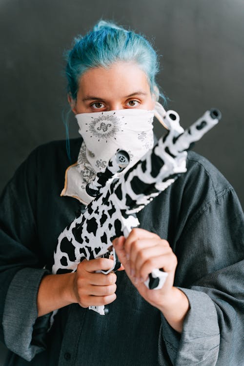 Photo of a Woman with Blue Hair Holding a Gun