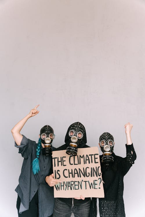 People in Black Long Sleeve Shirt Holding Brown Cardboard with Text