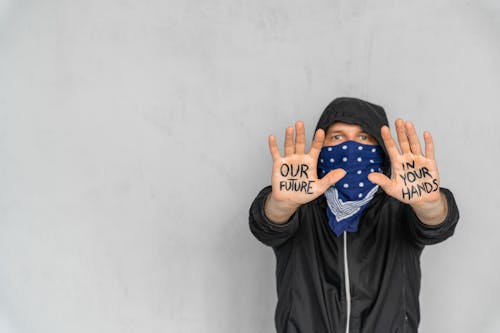 A Person Covering his Face with Scarf Showing Message Written on his Hands