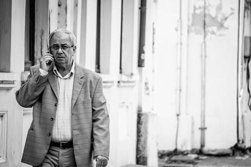 Free Grayscale Photograph of an Elderly Man Talking on the Phone Stock Photo