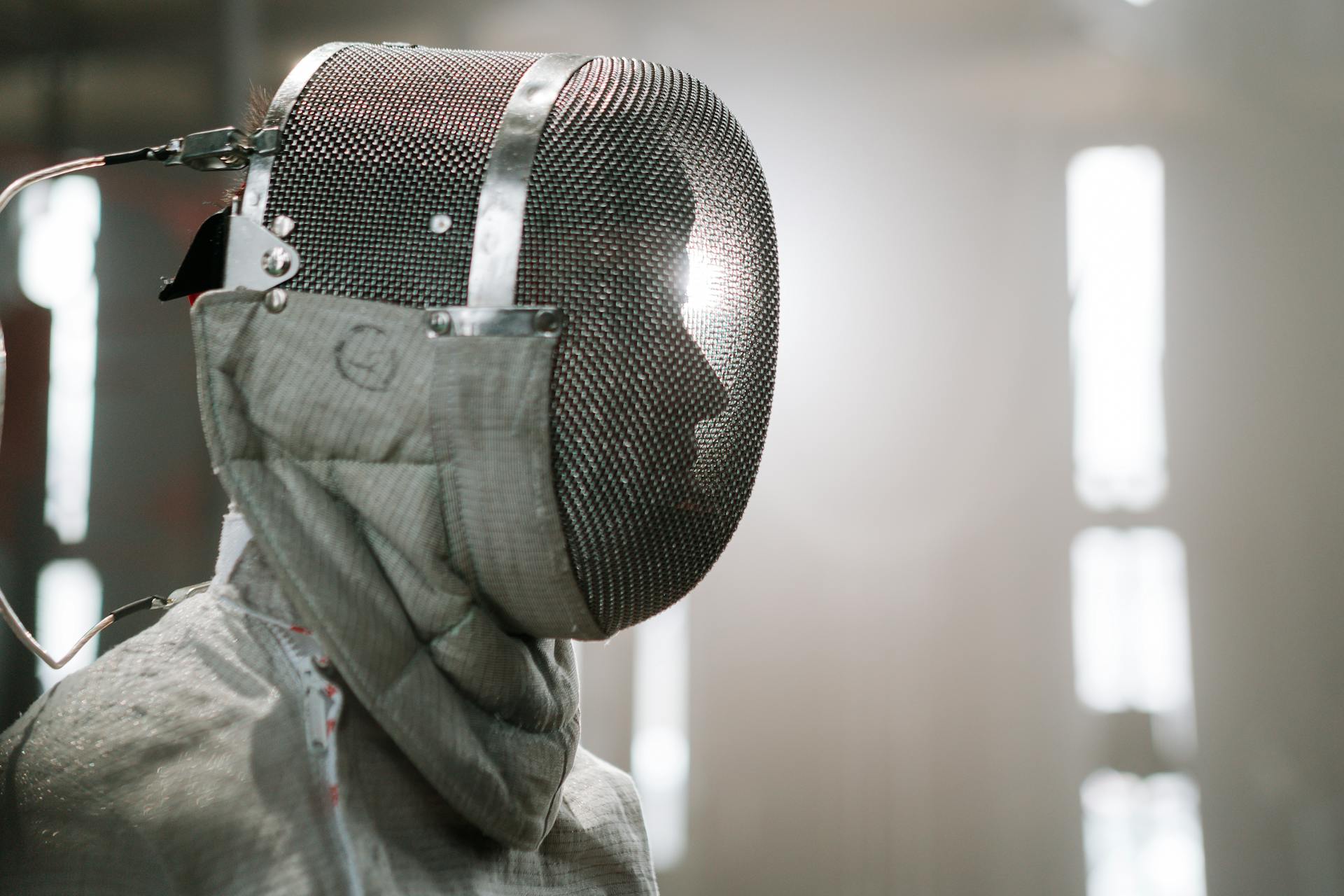 A close up on a profile view on an athlete wearing fencing mask