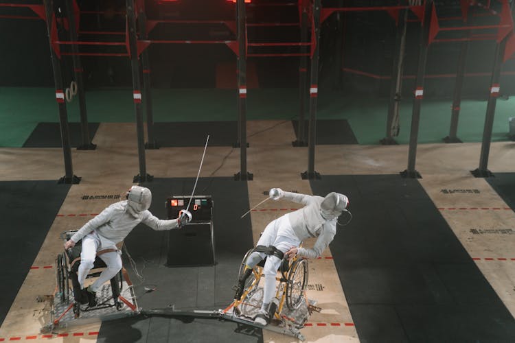 Two Paralympic Athletes Fencing While Wearing Fencing Sportswear 