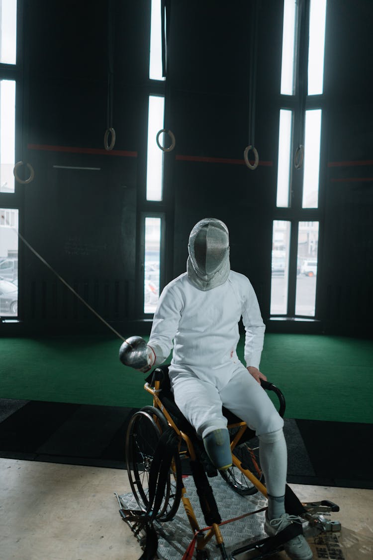 A Paralympic Athlete Sitting On Wheelchair And Holding A Foil