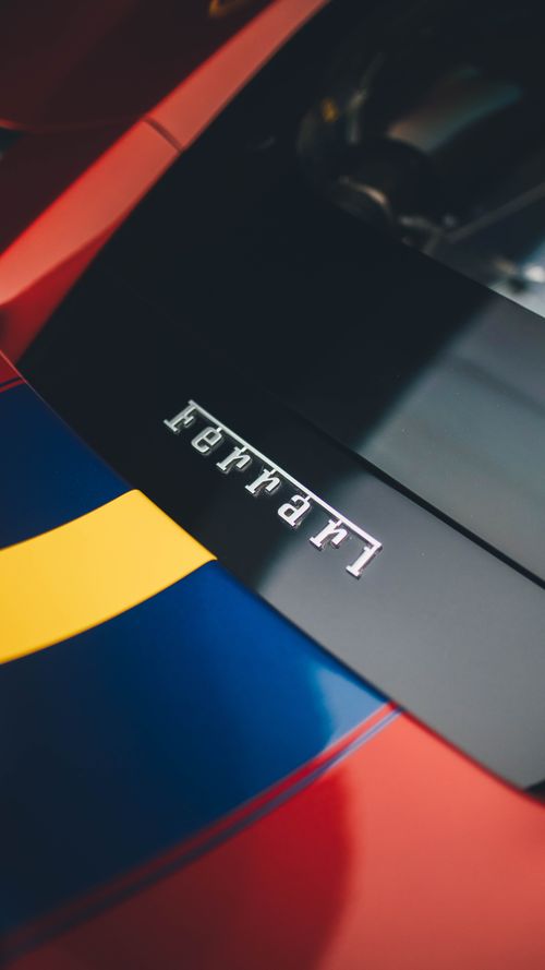 Free A striking close-up of a Ferrari logo on a colorful sports car hood, emphasizing luxury and design. Stock Photo